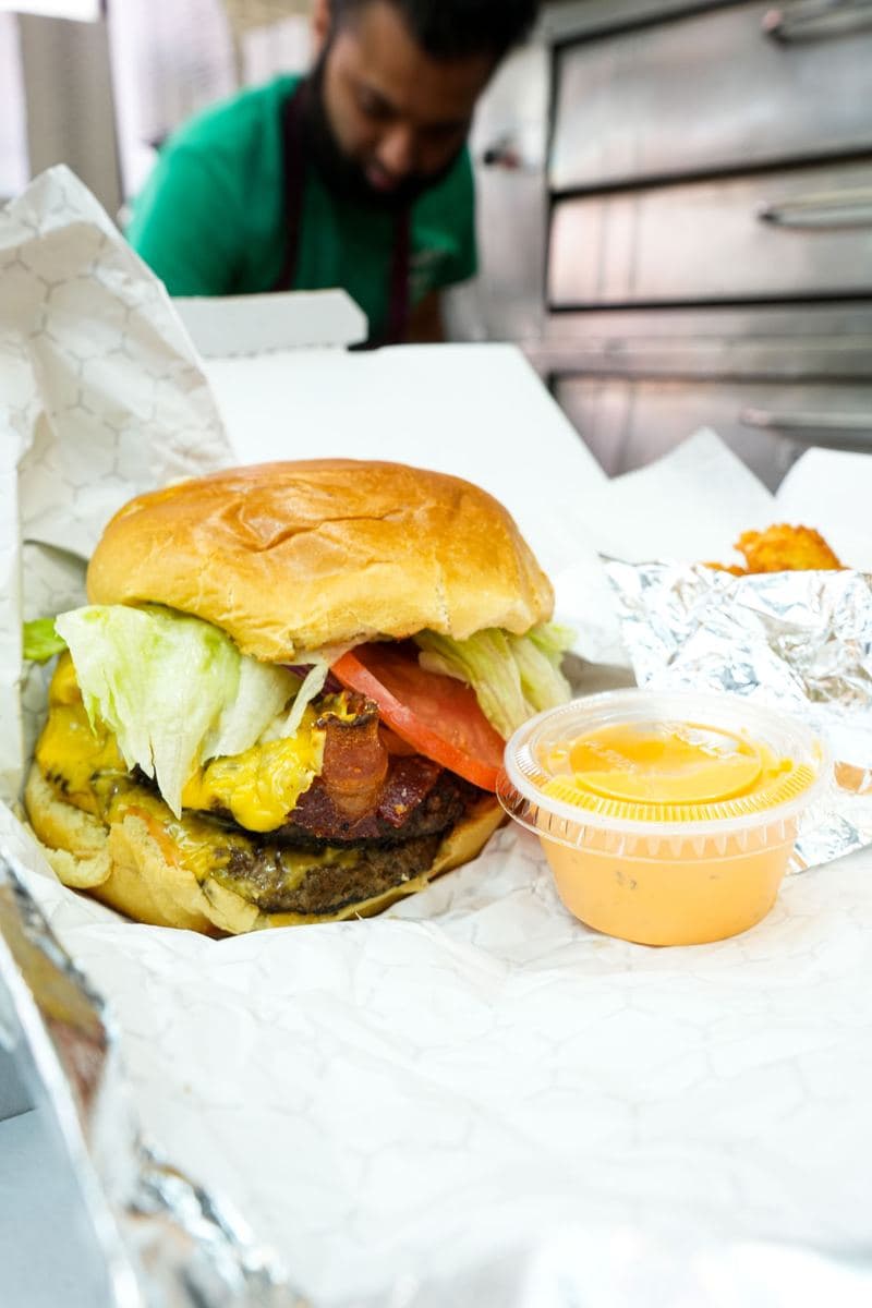 Bacon cheeseburger with American cheese, lettuce and tomato with a sauce cup
