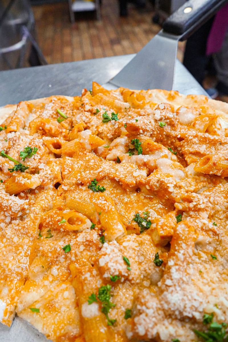 Baked penne pizza dusted with grated parmesan and parsley