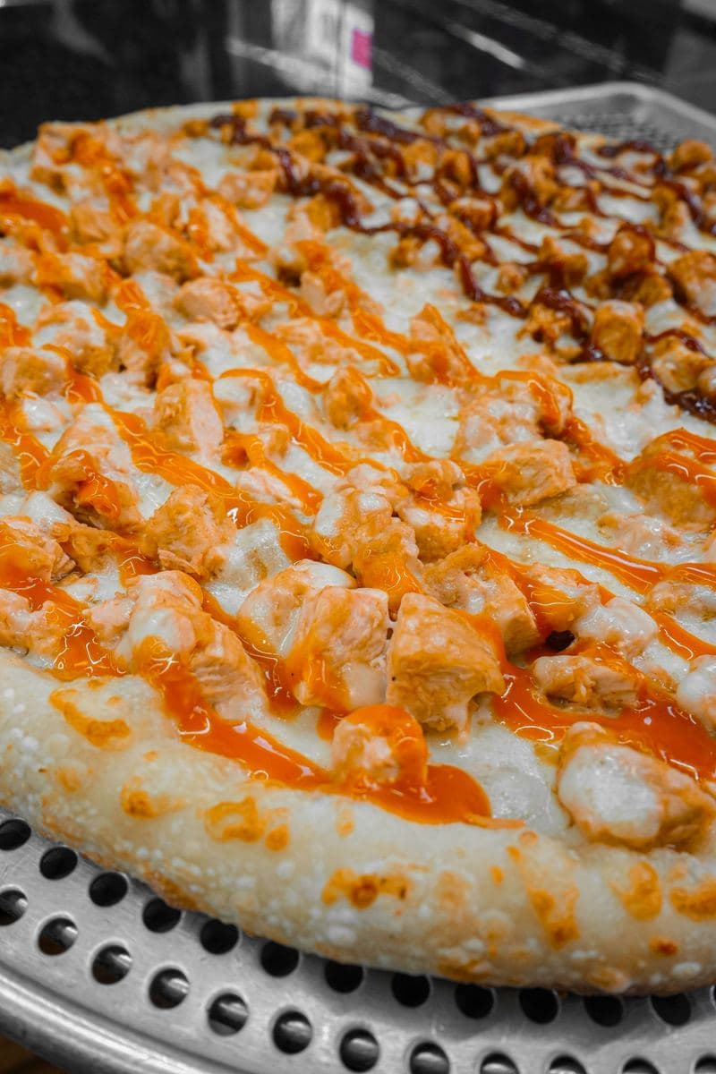 Buffalo chicken pizza finished with a drizzle of house hot sauce