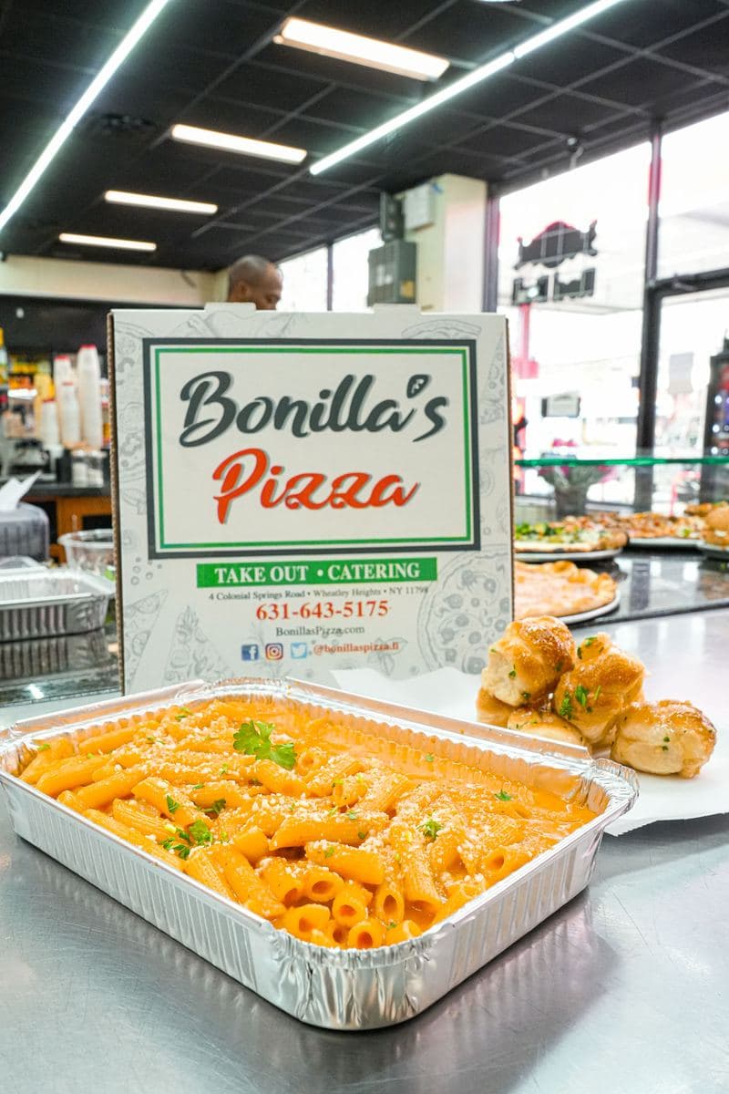 Catering tray of penne alla vodka with garlic knots and a Bonilla's box