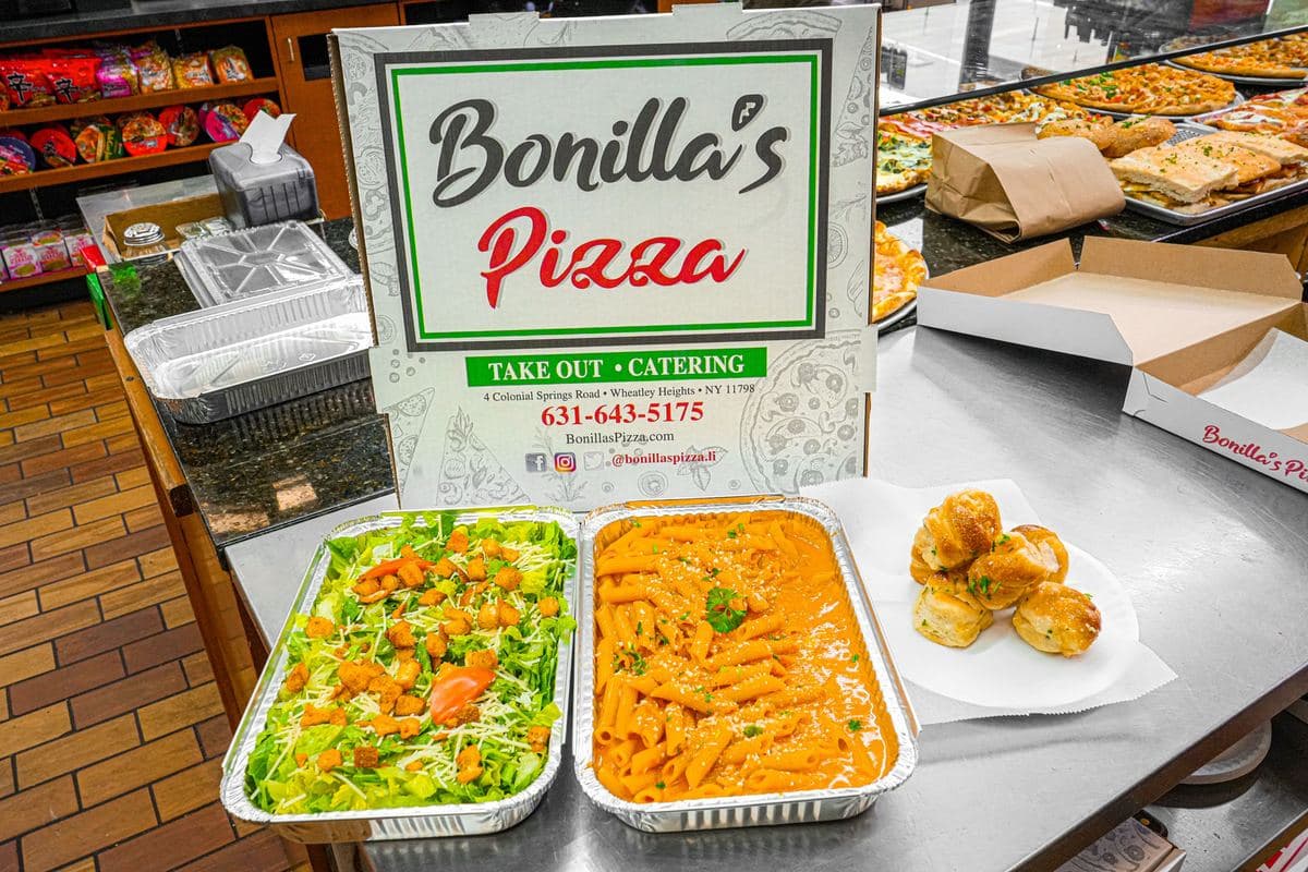 Close-up of catering trays: Caesar salad and penne alla vodka