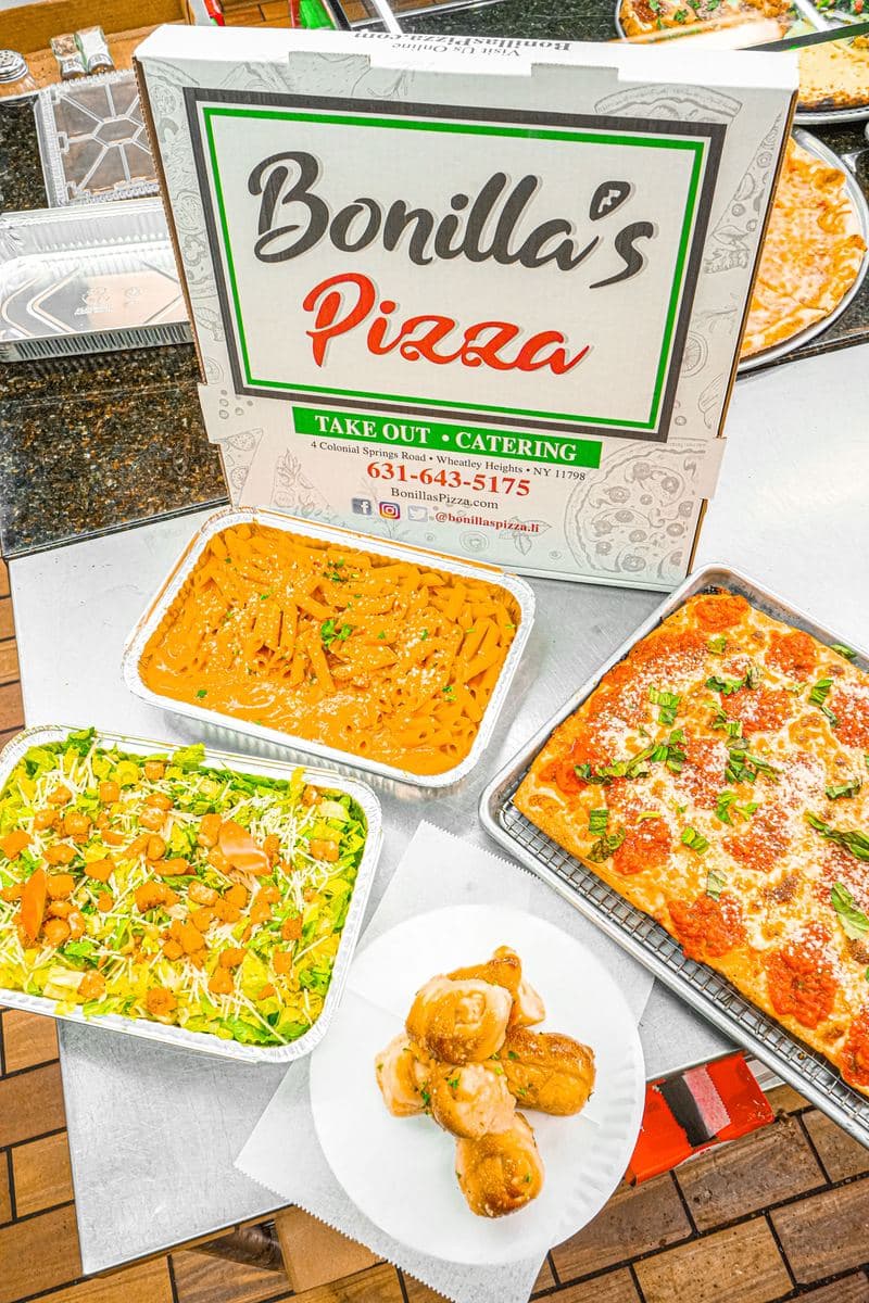 Three catering trays laid out with garlic knots and a Bonilla's box