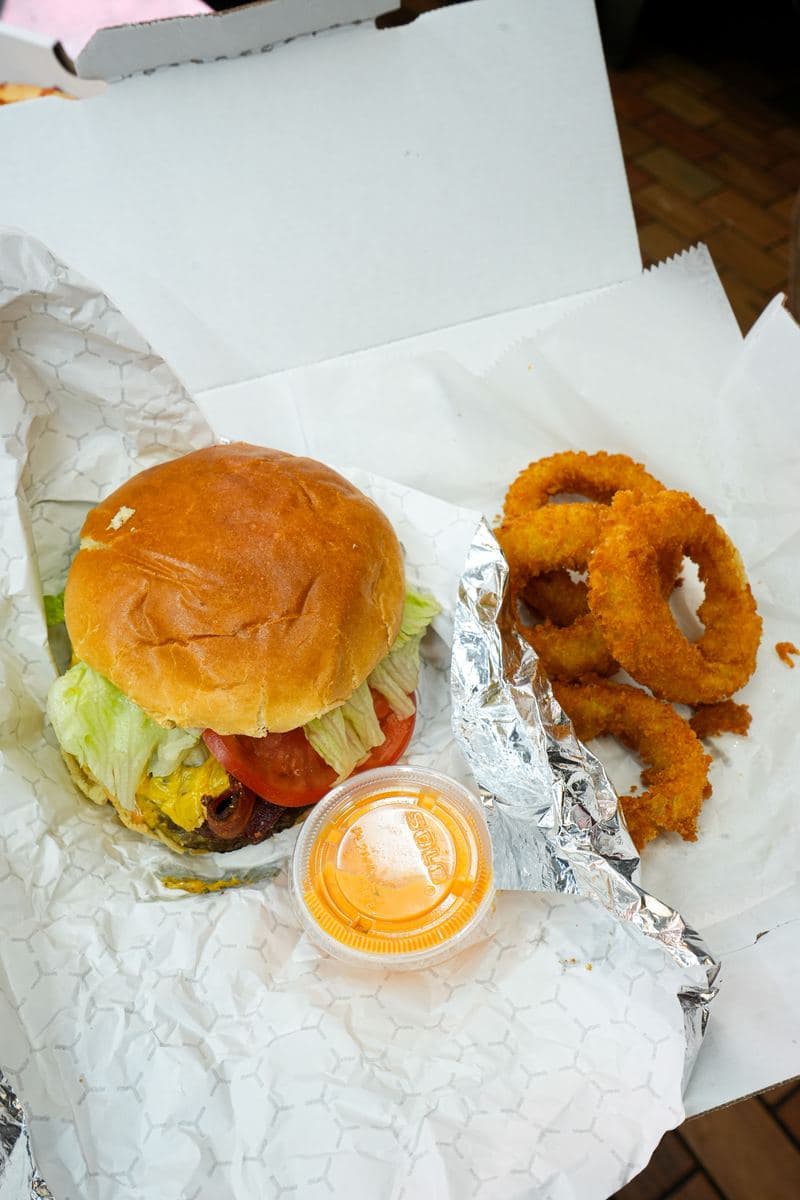 Cheeseburger with lettuce and tomato, served with onion rings and dipping sauce