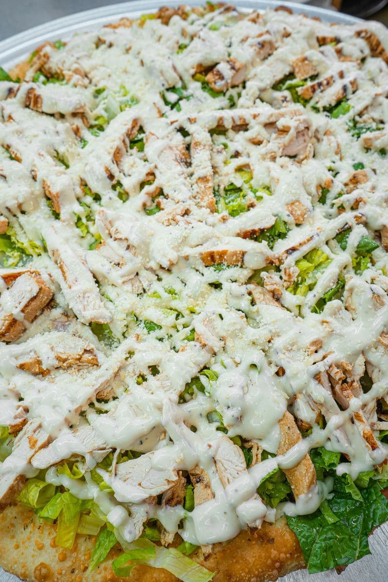 Chicken Caesar salad pizza, romaine and grilled chicken under a dressing drizzle