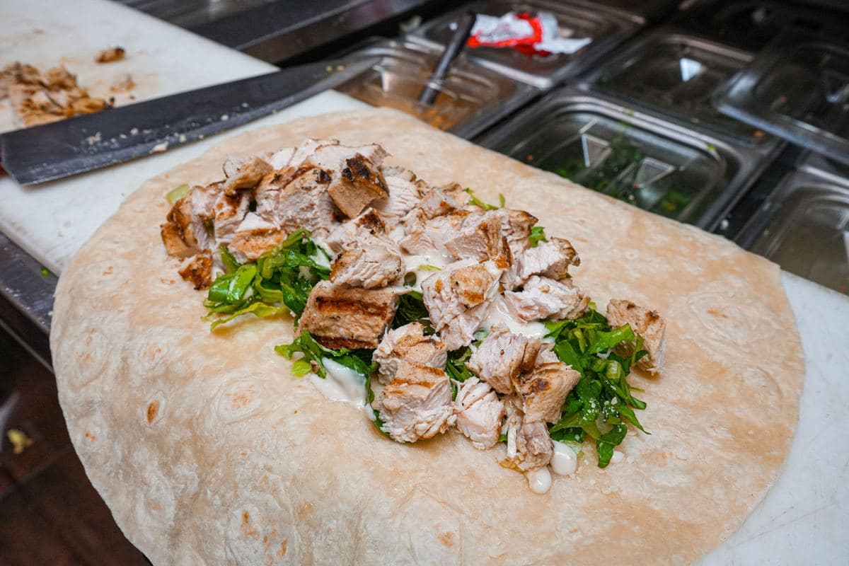Grilled chicken Caesar wrap being built on the prep line