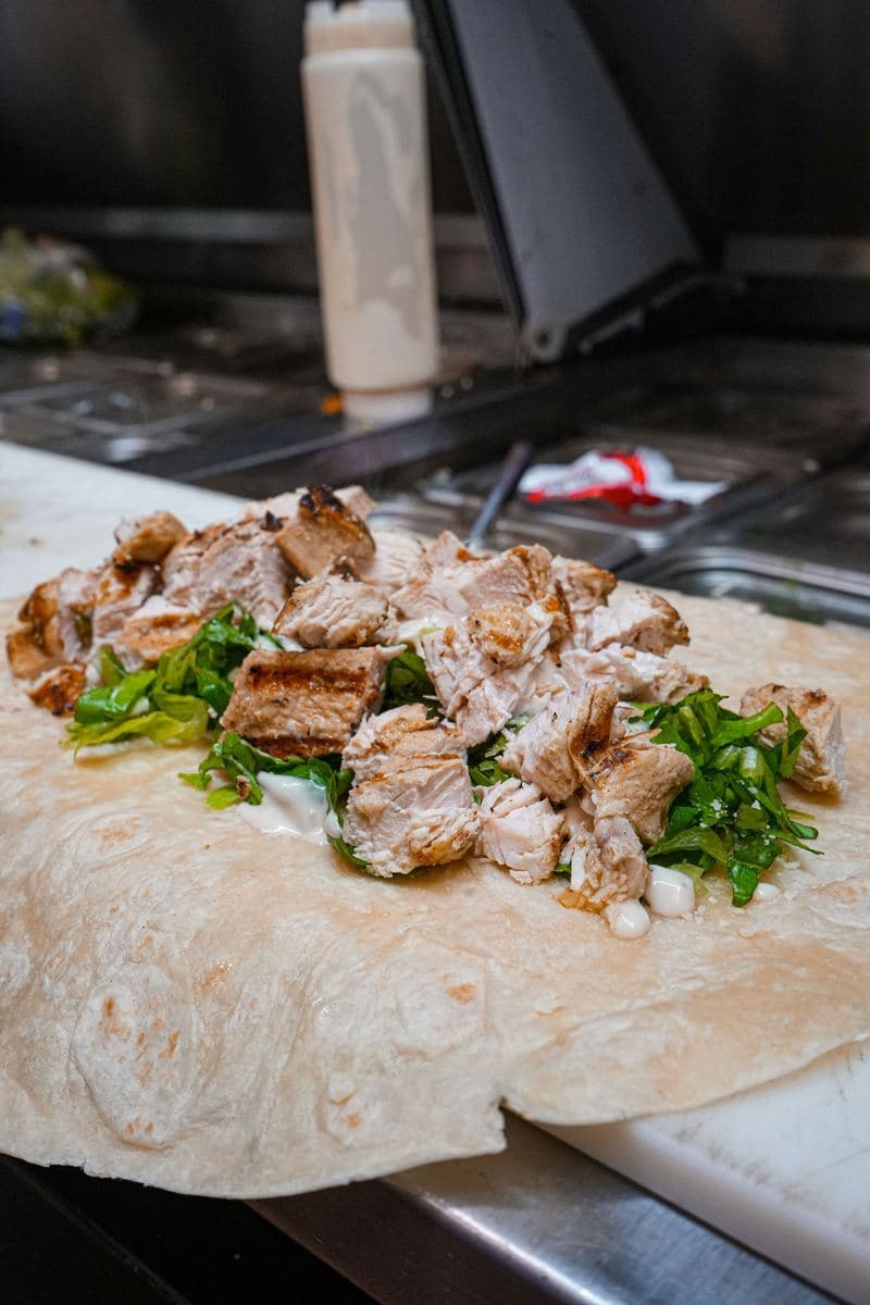 Grilled chicken and romaine laid out on a wrap before rolling