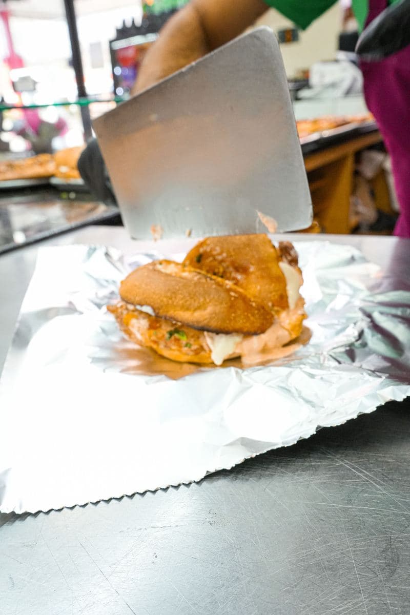 Chicken cutlet sandwich on foil being lifted with a spatula