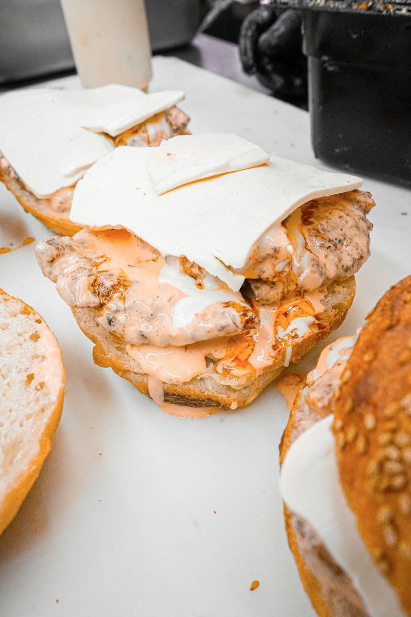 Open chicken cutlet sandwich layered with white cheese and house sauce