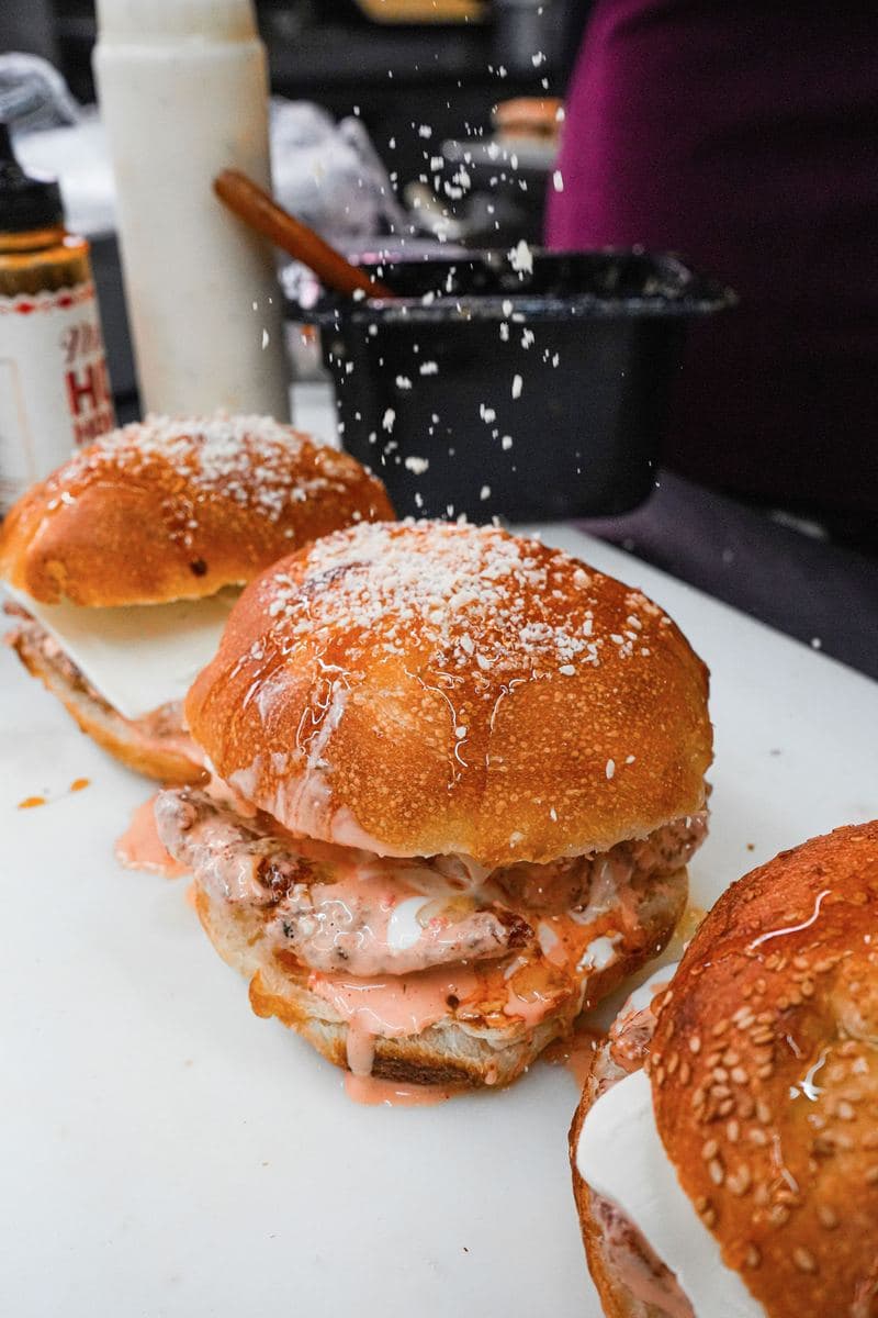 Grated parmesan falling over a chicken sandwich on a sesame roll
