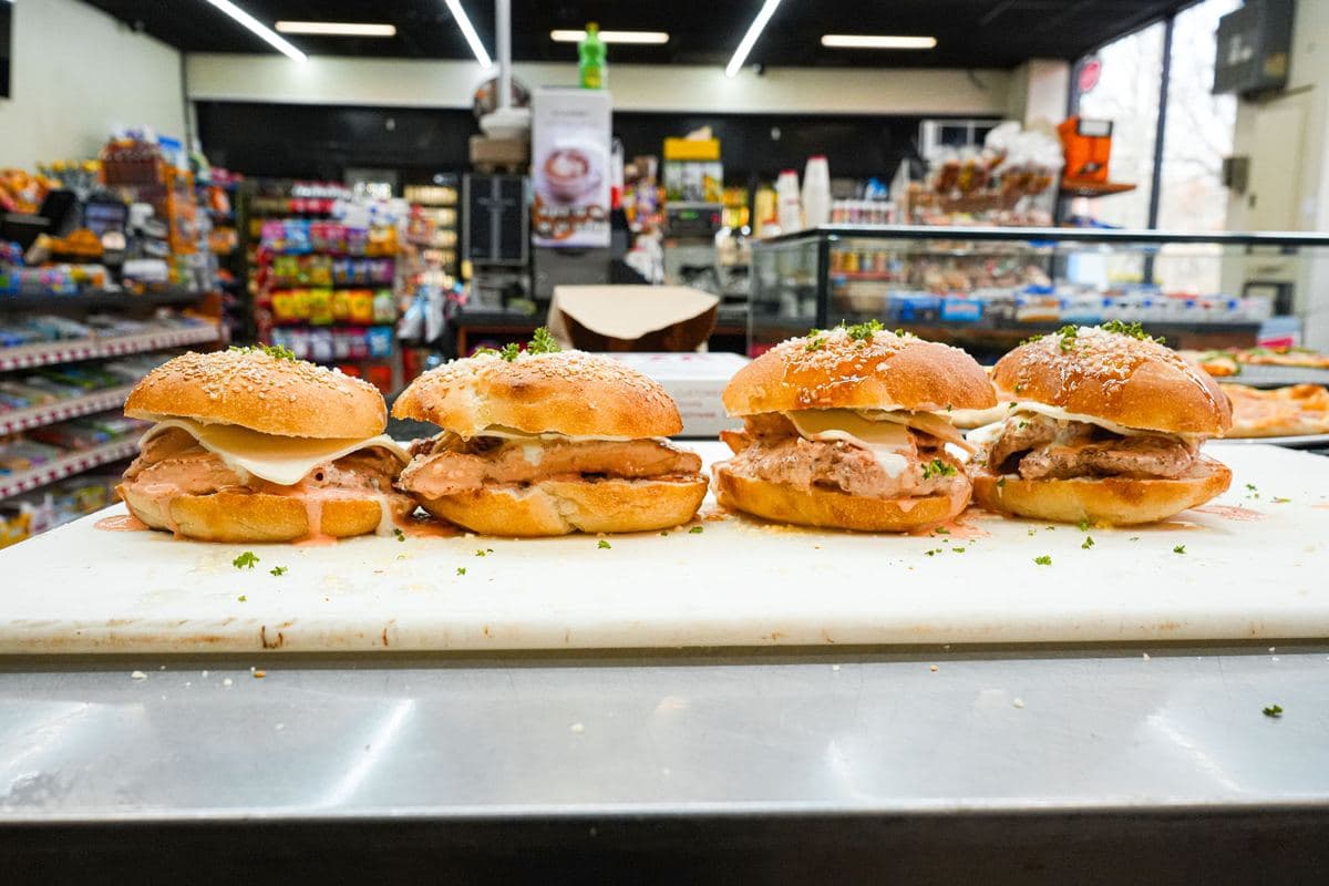 A row of chicken cutlet sandwiches lined up on the prep counter