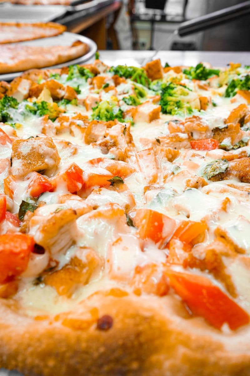 Close-up of chicken, tomato and roasted pepper on a white pie