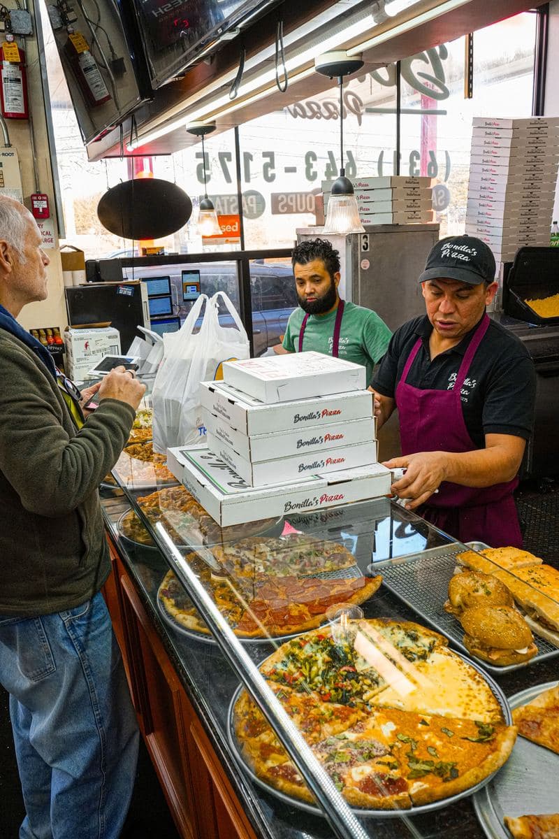 A customer at the counter as staff hand over a stack of Bonilla's boxes