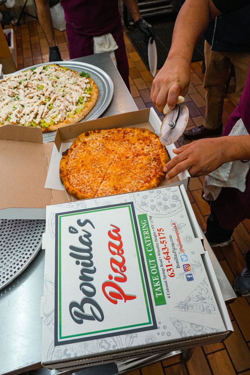 Cutting a personal cheese pie in a Bonilla's takeout box