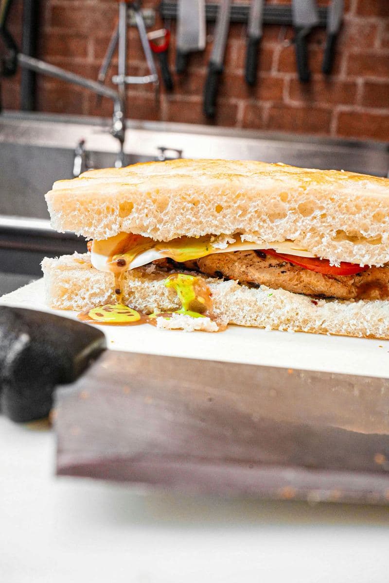 Focaccia hero closed and cut, chicken cutlet and cheese layered inside