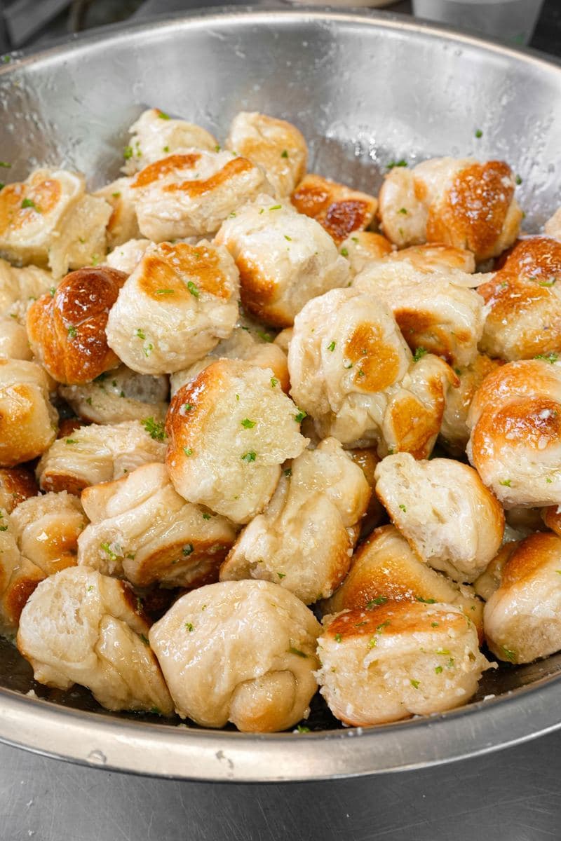 Tray of fresh-baked garlic knots tossed in garlic butter and parsley
