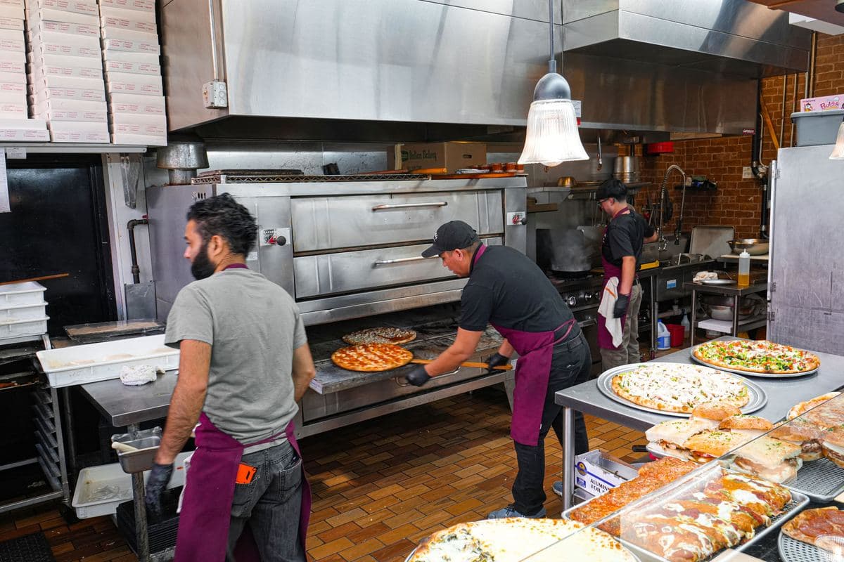 Two cooks working the deck oven in the Bonilla's kitchen