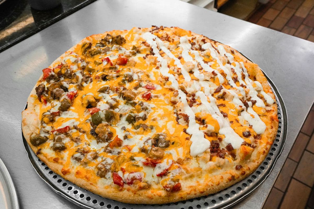 Loaded pizza with cheddar, peppers and a ranch drizzle across the top