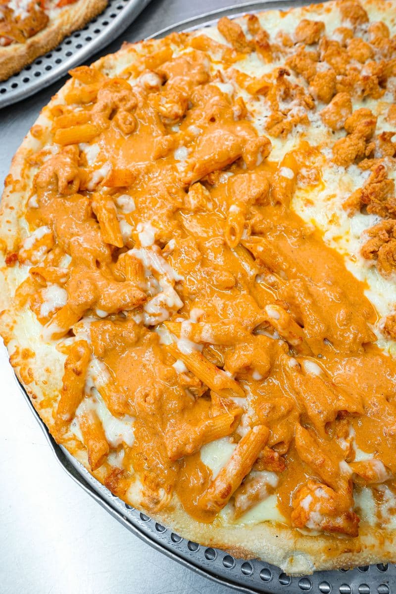 Close-up of penne in vodka sauce baked onto a pizza