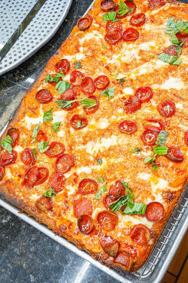 Overhead pepperoni Sicilian with basil scattered across the top