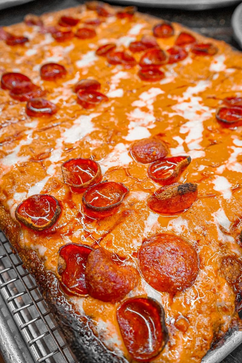 Close-up of cup-and-char pepperoni curling on a Sicilian pie