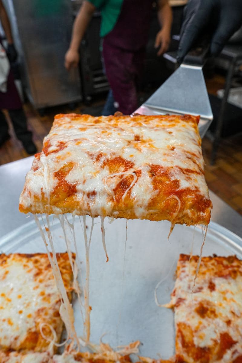 Cheese pull on a square Sicilian slice being lifted off the pan at Bonilla's